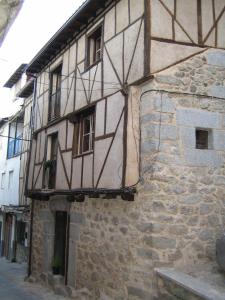 un vieux bâtiment en pierre avec des ombres sur son côté dans l'établissement La Serranilla, à San Esteban de la Sierra