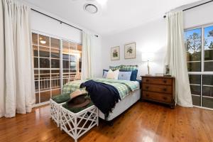 a bedroom with a bed and a chair and windows at The Stables Luxury Country Escape in Canungra