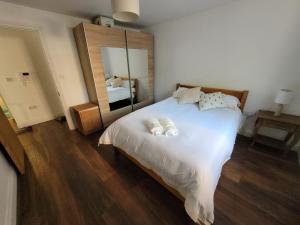 a bedroom with a large white bed and a mirror at Comfortable Two Bedroom Modern Apartment in London