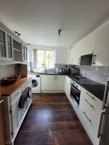 a kitchen with white cabinets and a wooden floor at Comfortable Two Bedroom Modern Apartment in London