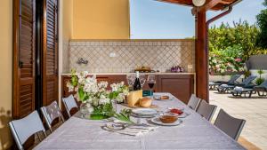 einen Tisch mit Platten und Blumen darüber in der Unterkunft Villa delle Sirene 6, Emma Villas in Valderice