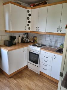 a kitchen with white cabinets and a stove top oven at Trondheim/Nardo in Trondheim