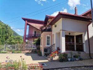 ein Haus mit einem Zaun und Blumen davor in der Unterkunft VILA ANA in Băile Herculane