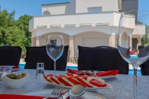 a table with wine glasses and a plate of food at Villa Ramljak in Mostar