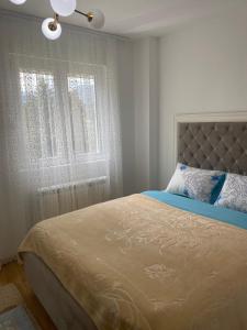 a bedroom with a bed and a window with curtains at Pirlitor Mountain Apartment in Žabljak