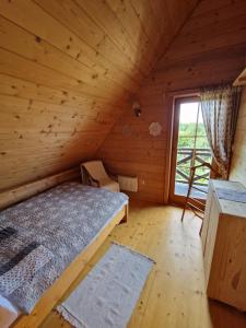 ein Schlafzimmer in einem Blockhaus mit einem Bett und einem Fenster in der Unterkunft Dom Letnisowkowy Basiówka in Bodzentyn