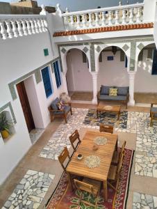 salon z drewnianym stołem i krzesłami w obiekcie Beit El Ezz - la grande w mieście Ouled Yaneg