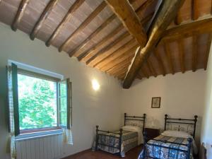 Un dormitorio con dos camas y una ventana. en Agriturismo la Peschiera, en Casole dʼElsa