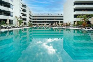 a large swimming pool with chairs and a building at HOVIMA Suites Costa Adeje in Adeje
