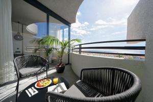 a balcony with two chairs and a table with food on it at HOVIMA Suites Costa Adeje in Adeje