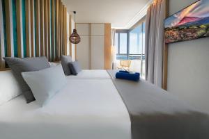 a bedroom with two white beds and a large window at HOVIMA Suites Costa Adeje in Adeje