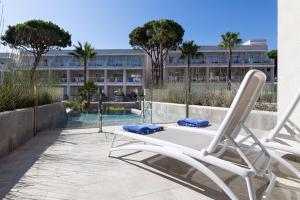 a pair of chairs on a patio with a building at Hipotels Barrosa Palace & Spa in Chiclana de la Frontera