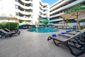 a swimming pool with lounge chairs and a building at HOVIMA Suites Costa Adeje in Adeje