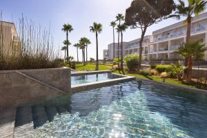 a swimming pool in a building with palm trees at Hipotels Barrosa Palace & Spa in Chiclana de la Frontera