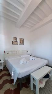 a white bedroom with a large bed with two pillows at La casa di Fa' in Siena