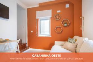 sala de estar con paredes de color naranja y sofá blanco en Cabanas do avô João, en Nazaré