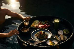 una persona en el agua con una mesa de comida en Minos Palace Hotel & Suites - Adults Only, en Agios Nikolaos