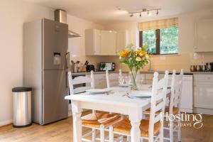 a kitchen with a white table with a vase of flowers at Walkers Lodge In The Heart Of The Chilterns With Incredible Views in Henley on Thames