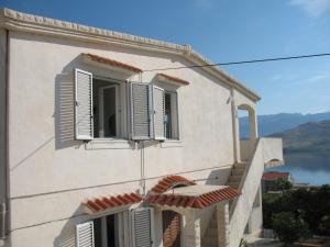 a building with white windows and a view of a lake at Apartments Vera in Pag