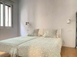 een witte slaapkamer met een bed en 2 kussens bij Apartamento Ayla Catedral in Pamplona