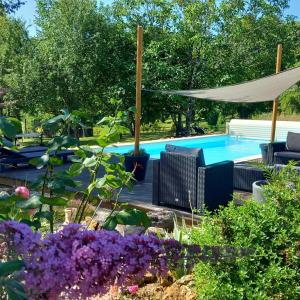 Lussas-et-Nontronneau的住宿－Le Petit Coin - LPC Dordogne Holidays，紫色花卉花园中的游泳池