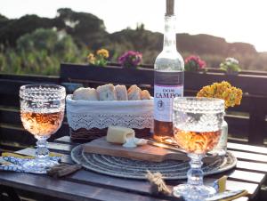 a table with a bottle of wine and a basket of bread at Shanti Farm Meco in Sesimbra