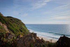 a beach with a kite flying over the ocean at Shanti Farm Meco in Sesimbra