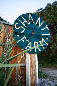 Un cartello blu che dice gardenarma su un palo di legno di Shanti Farm Meco a Sesimbra