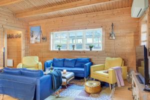 a living room with blue couches and yellow chairs at Feriehus - Ramløse, Danmark in Helsinge