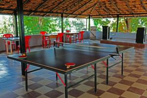 a ping pong table in a room with red chairs at Mothers Bounty by Lazo , Coorg in Madikeri