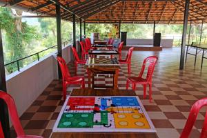 a restaurant with tables and red chairs on a checkered floor at Mothers Bounty by Lazo , Coorg in Madikeri