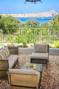 a patio with two couches and a table with two glasses on it at Welcoming Rhodes Villa 2 Bedrooms Villa Thea Stunning Sea and BBQ Lindos in Lindos