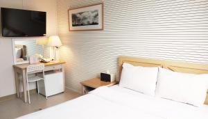 a bedroom with a bed and a desk with a television at Golden Park Hotel in Jeju