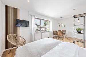 a white bedroom with a bed and a table and chairs at Ruhiges und zentrales Apartment in Hüttenfeld in Lampertheim