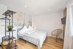 ein weißes Schlafzimmer mit einem Bett und einem Stuhl in der Unterkunft Ruhiges und zentrales Apartment in Hüttenfeld in Lampertheim