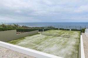 a tennis court with the ocean in the background at Windmill Beachfront Villa in Colares