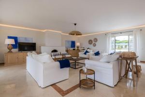 a living room with white couches and a tv at Windmill Beachfront Villa in Colares