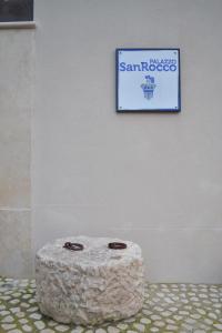 un cartel en una pared con un taburete de piedra delante de una pared en Palazzo San Rocco Residenza Gentilizia, en Sperlonga