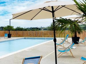 ein Sonnenschirm und Stühle neben einem Pool in der Unterkunft DOMAINE SAÂNE ET MER in Quiberville