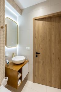 La salle de bains est pourvue d'un lavabo et d'une porte en bois. dans l'établissement Vatër Apartments, à Tirana