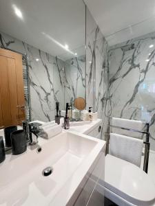 a bathroom with a white sink and a marble wall at 2 Southwell Road - Luxurious City Centre Apartments in Norwich