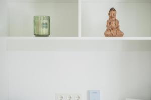 a shelf with a buddha statue and a candle at Central City Suits in Wiener Neustadt