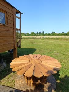 a wooden umbrella sitting on a table in a field at Roulotte Ô Rêves Atypiques in Boucé