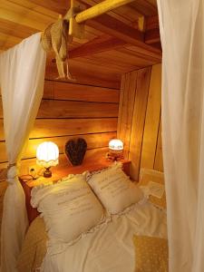 a bed with two lamps and two pillows on it at Roulotte Ô Rêves Atypiques in Boucé