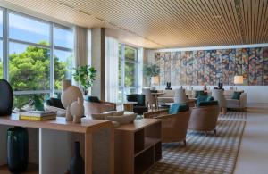 a waiting room with tables and chairs and windows at Bluesun Hotel Maestral in Brela