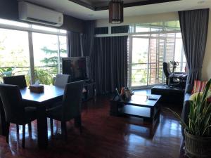 een woonkamer met een tafel en stoelen en een woonkamer met ramen bij The Seaside One Huahin in Hua Hin