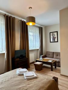 a bedroom with a bed and a couch and a table at Hotelik Korona in Raszyn