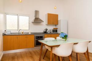 a kitchen with a table and some white chairs at Fénix House in Arco da Calheta