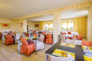 un restaurante con mesas, sillas naranjas y mesa en Erzgebirgshotel Freiberger Höhe, en Eppendorf