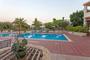 a pool at a resort with a bench and trees at Esperia apartments in Platanes